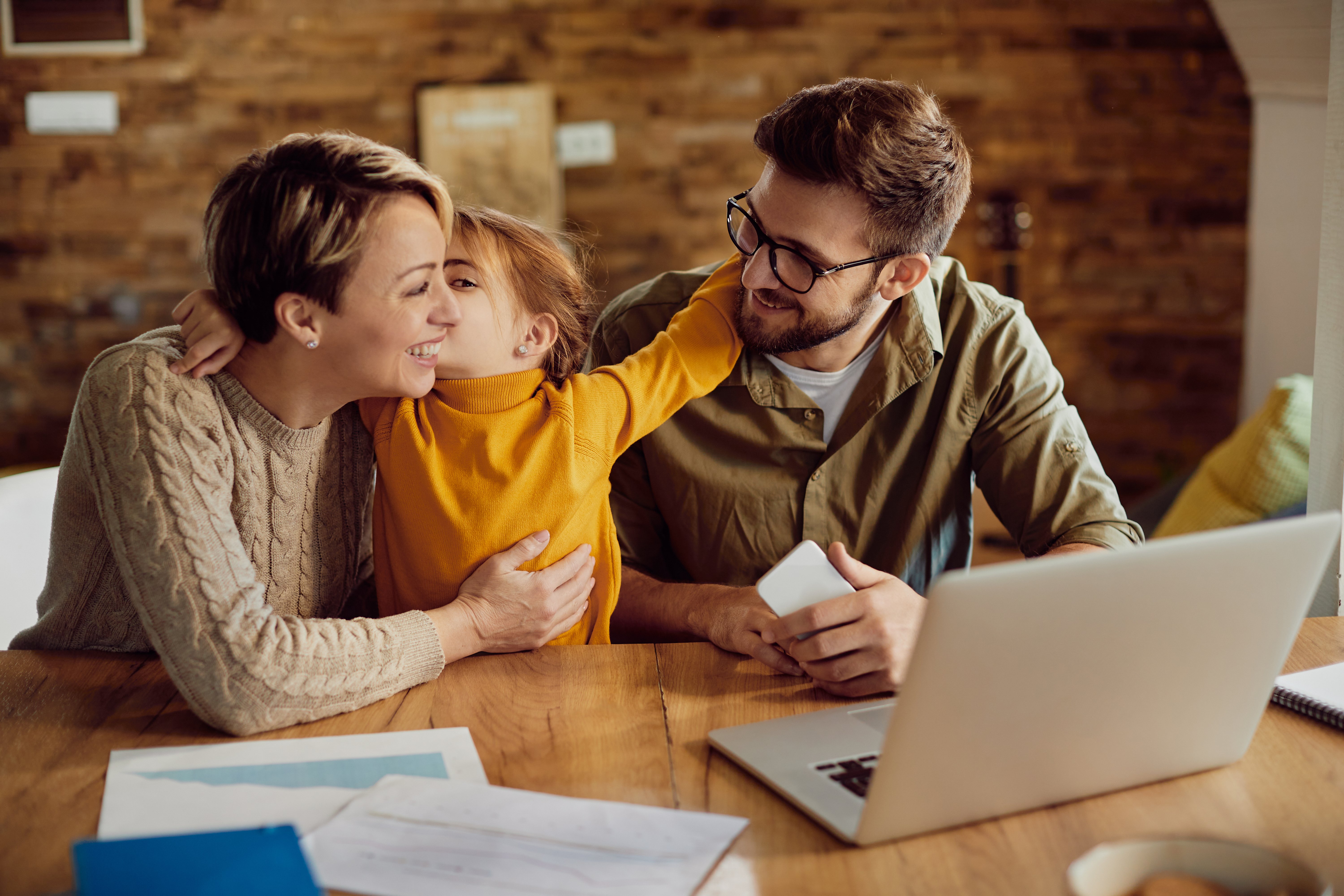 happy-daughter-embracing-kissing-her-working-parents-home