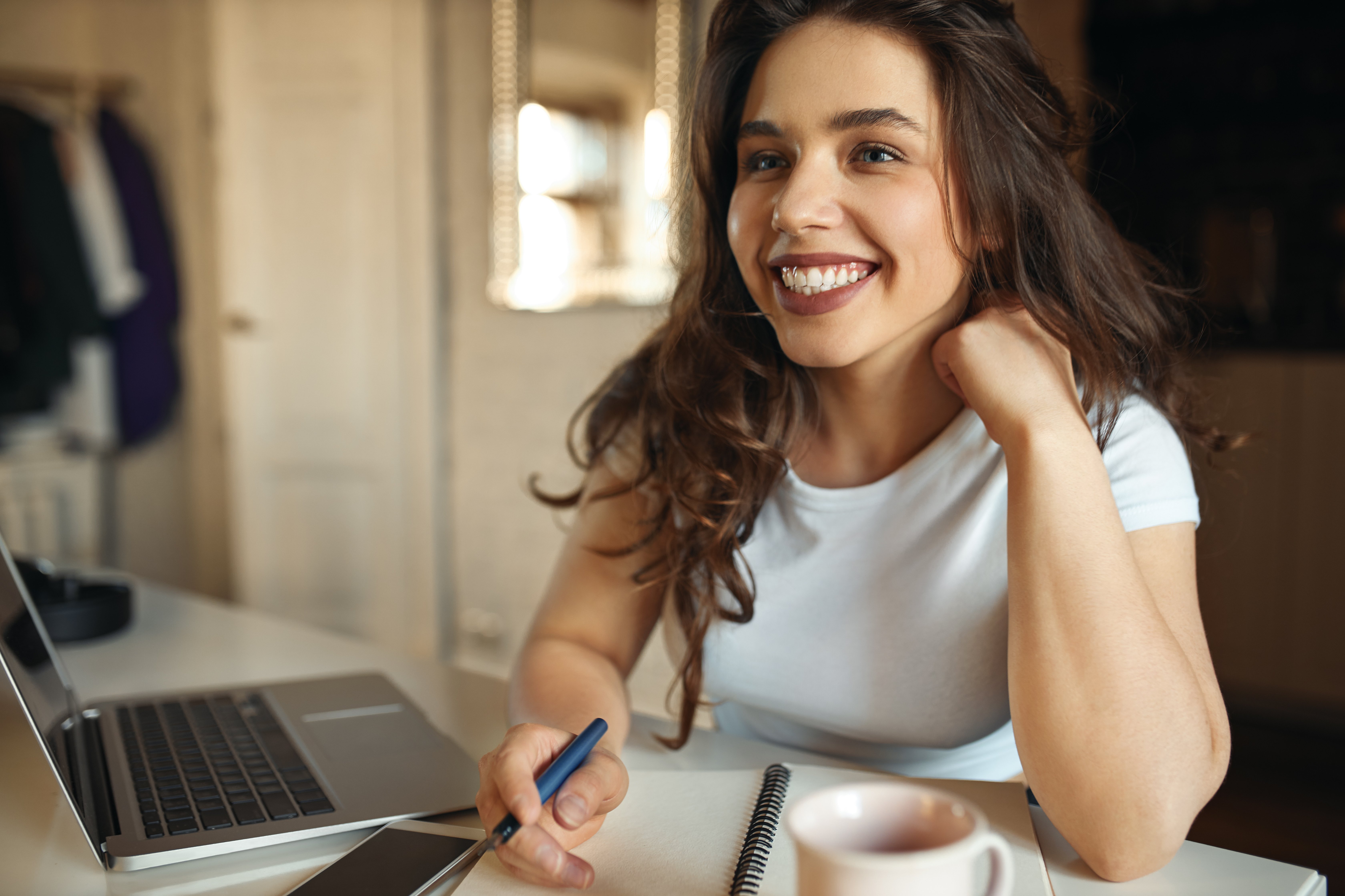 happy-young-plus-size-woman-making-notes-her-copybook-using-wireless-internet-connection-laptop