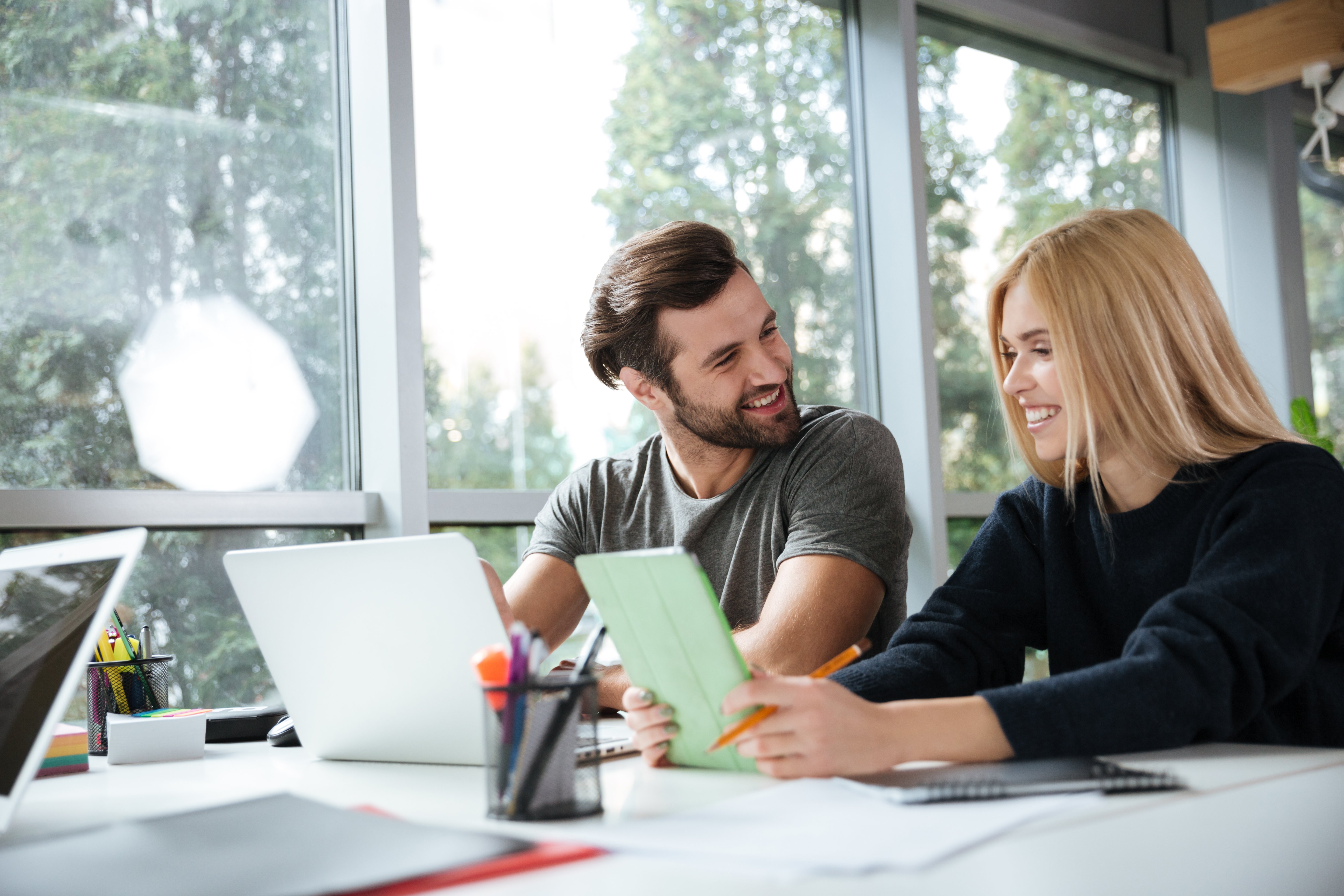 smiling-young-colleagues-sitting-office-coworking (1)